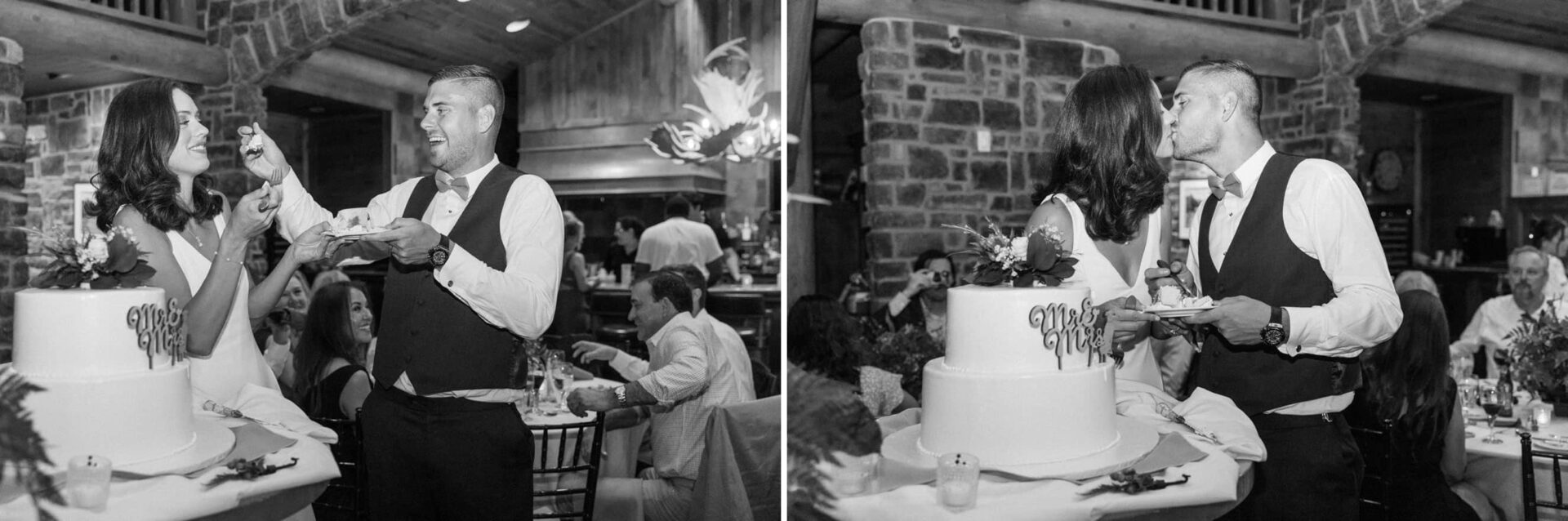 A couple dressed in wedding attire cuts and shares a piece of cake at The Ridge at Back Brook. They kiss in front of the cake, which is decorated with flowers and a "Just Married" sign. Guests are seated at tables in the background, all enjoying the scenic beauty of this New Jersey country club.