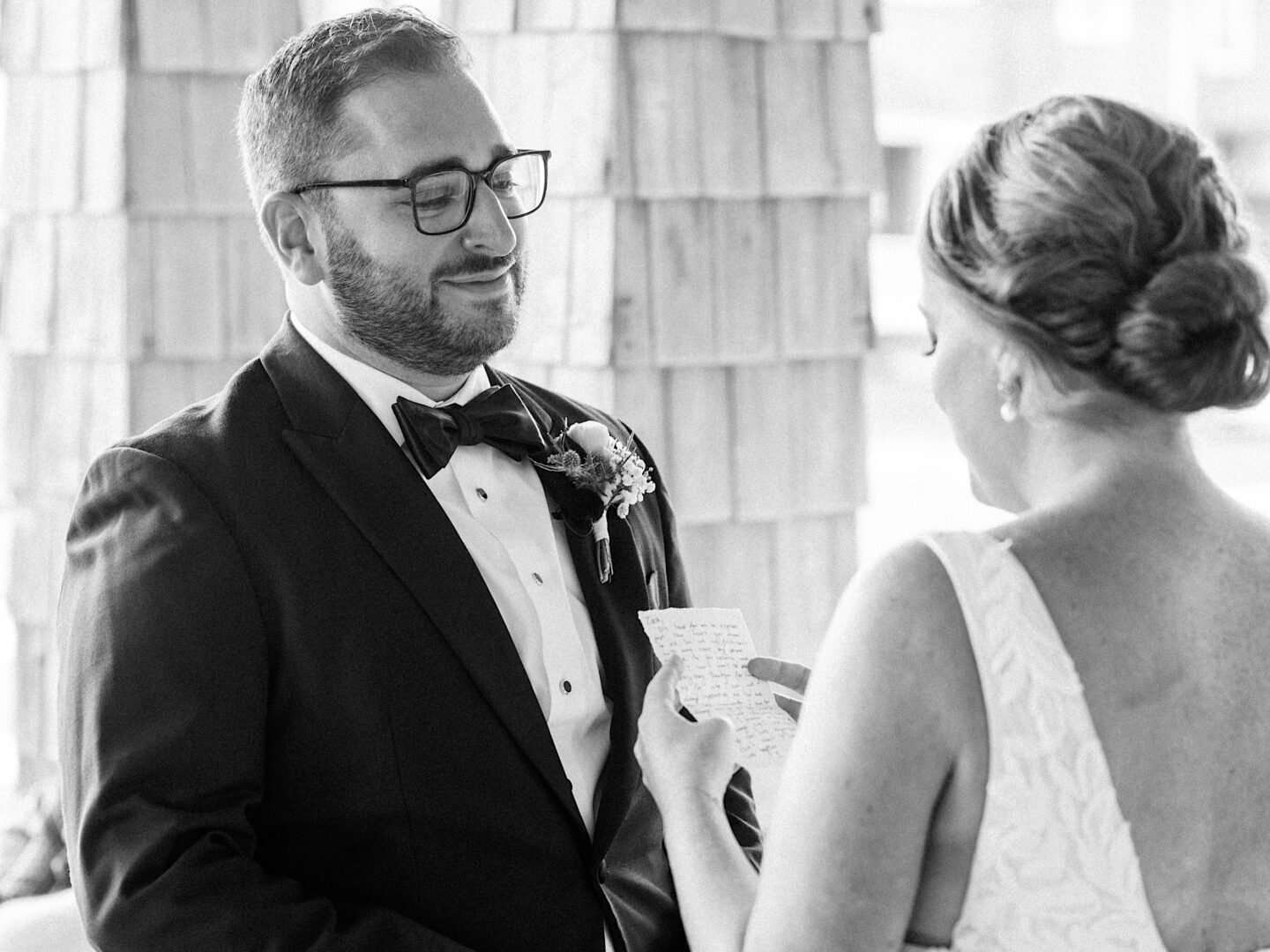 At the Corinthian Yacht Club of Cape May, a couple in formal attire exchange vows during their wedding ceremony, with the bride reading from a handwritten note.