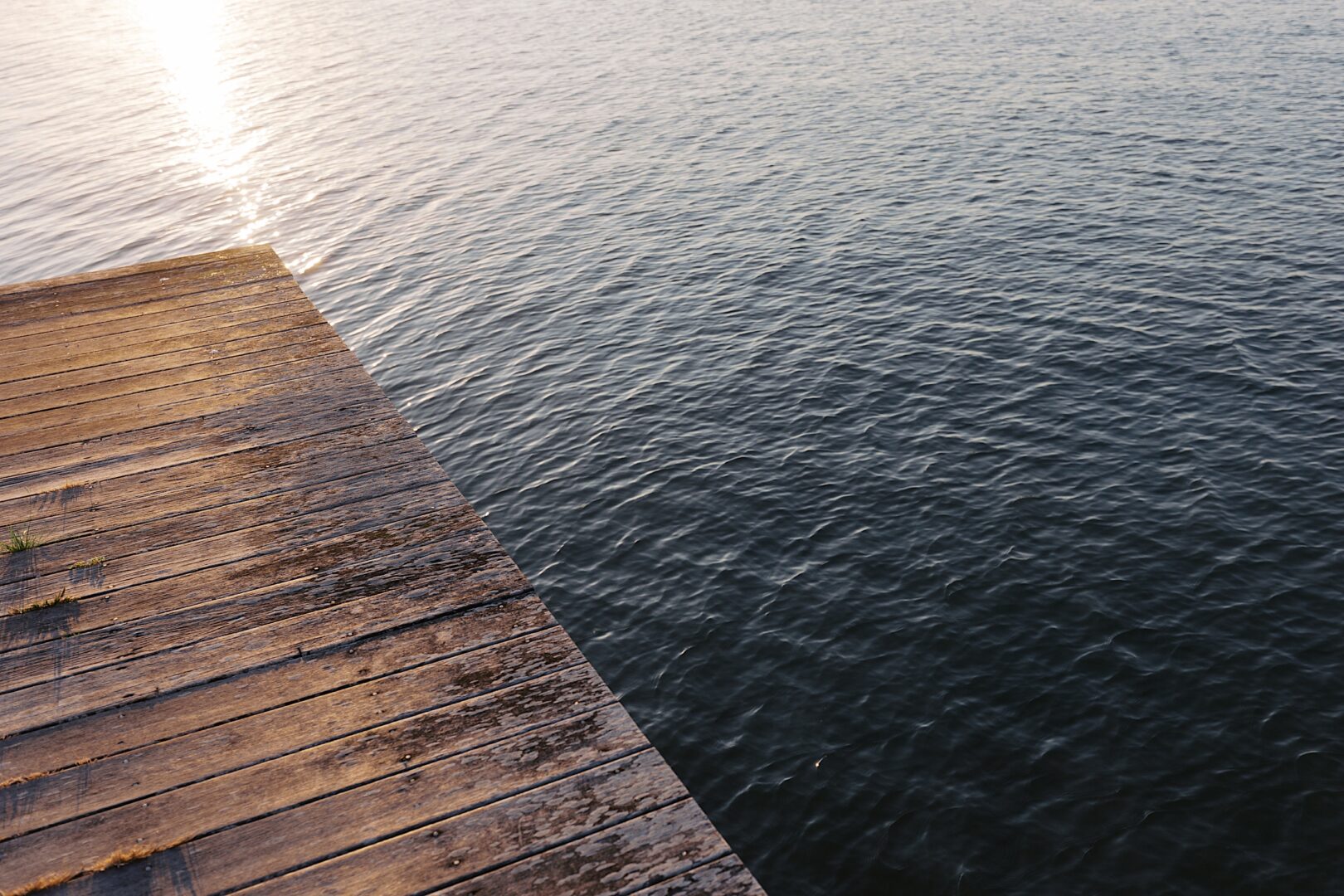 Sunlit wooden pier extending over rippling water at the Corinthian Yacht Club of Cape May sets the perfect backdrop for a dream wedding.