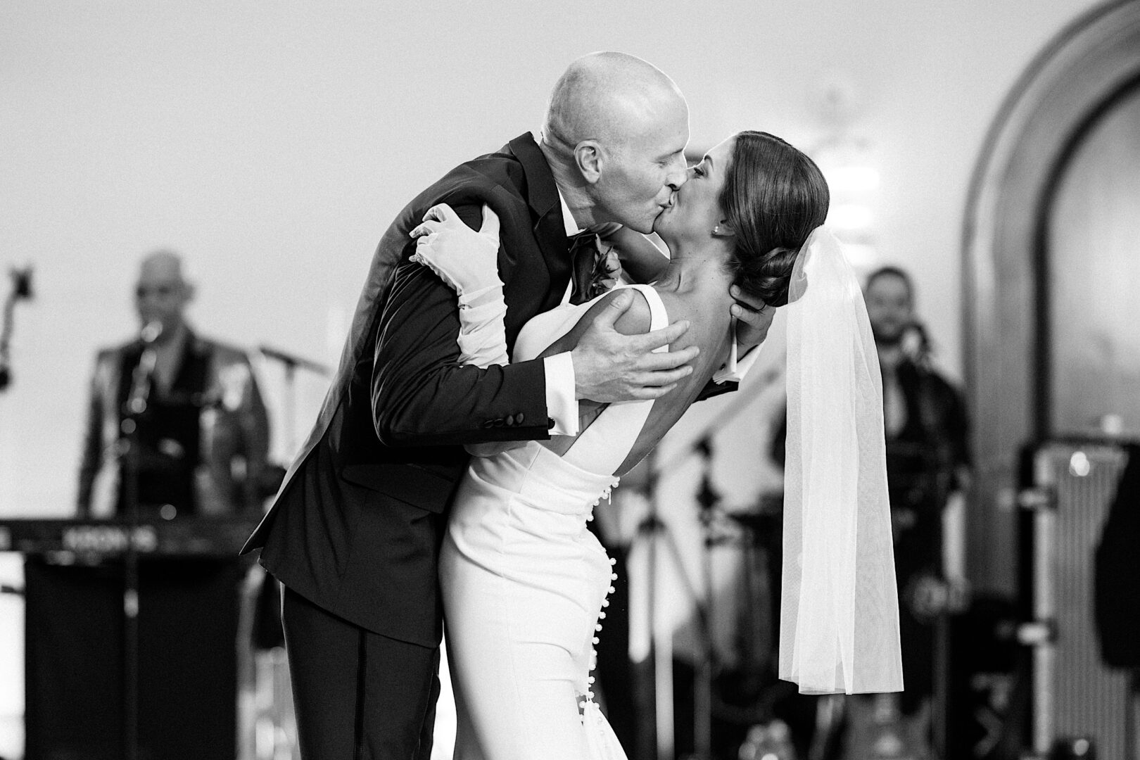 During their magical Tilling House wedding, the couple shares a tender kiss on the dance floor as musicians create an enchanting background melody.