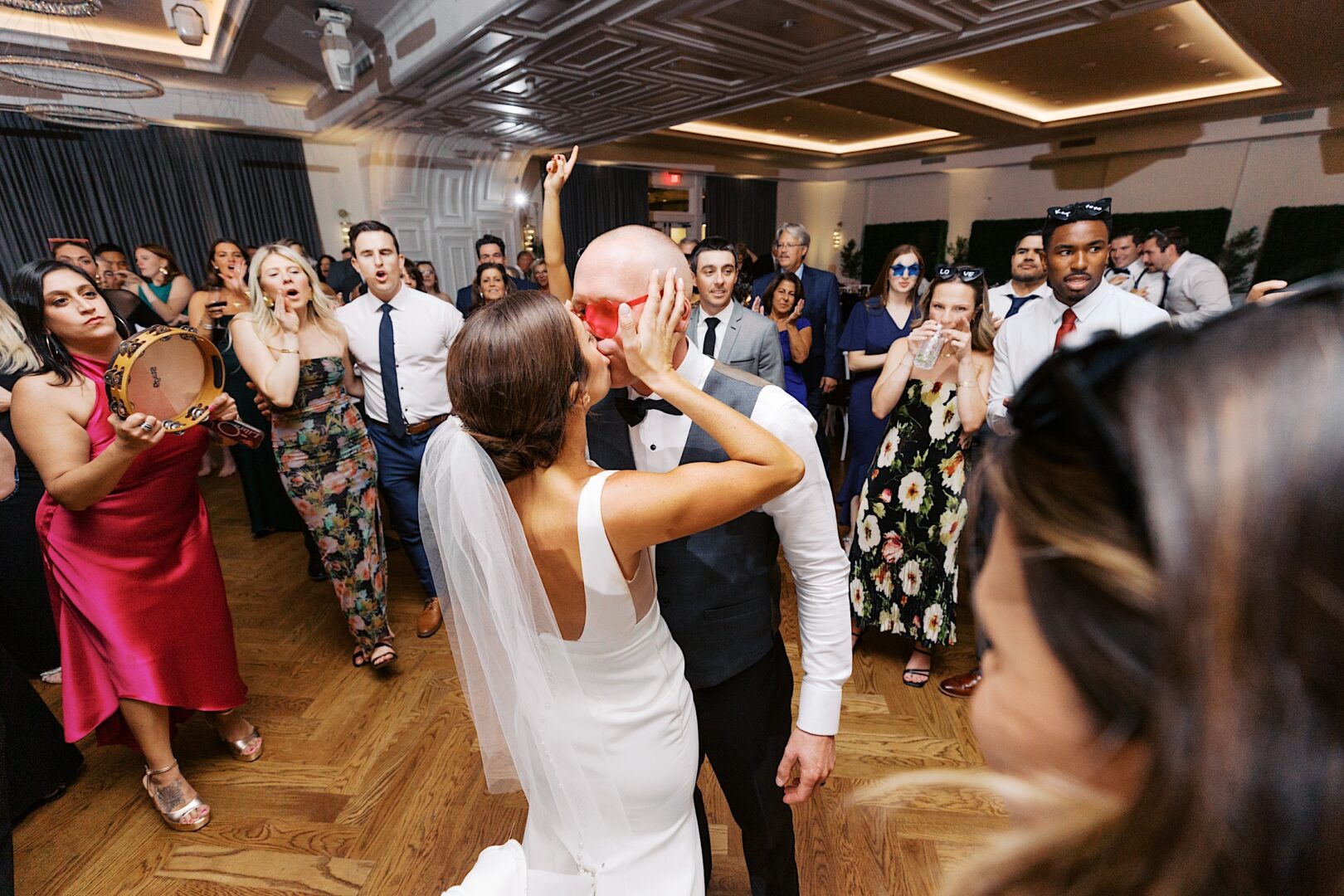 At The Tilling House wedding, a bride playfully smashes cake into the groom's face on the dance floor, prompting cheers and a flurry of camera flashes from delighted guests.