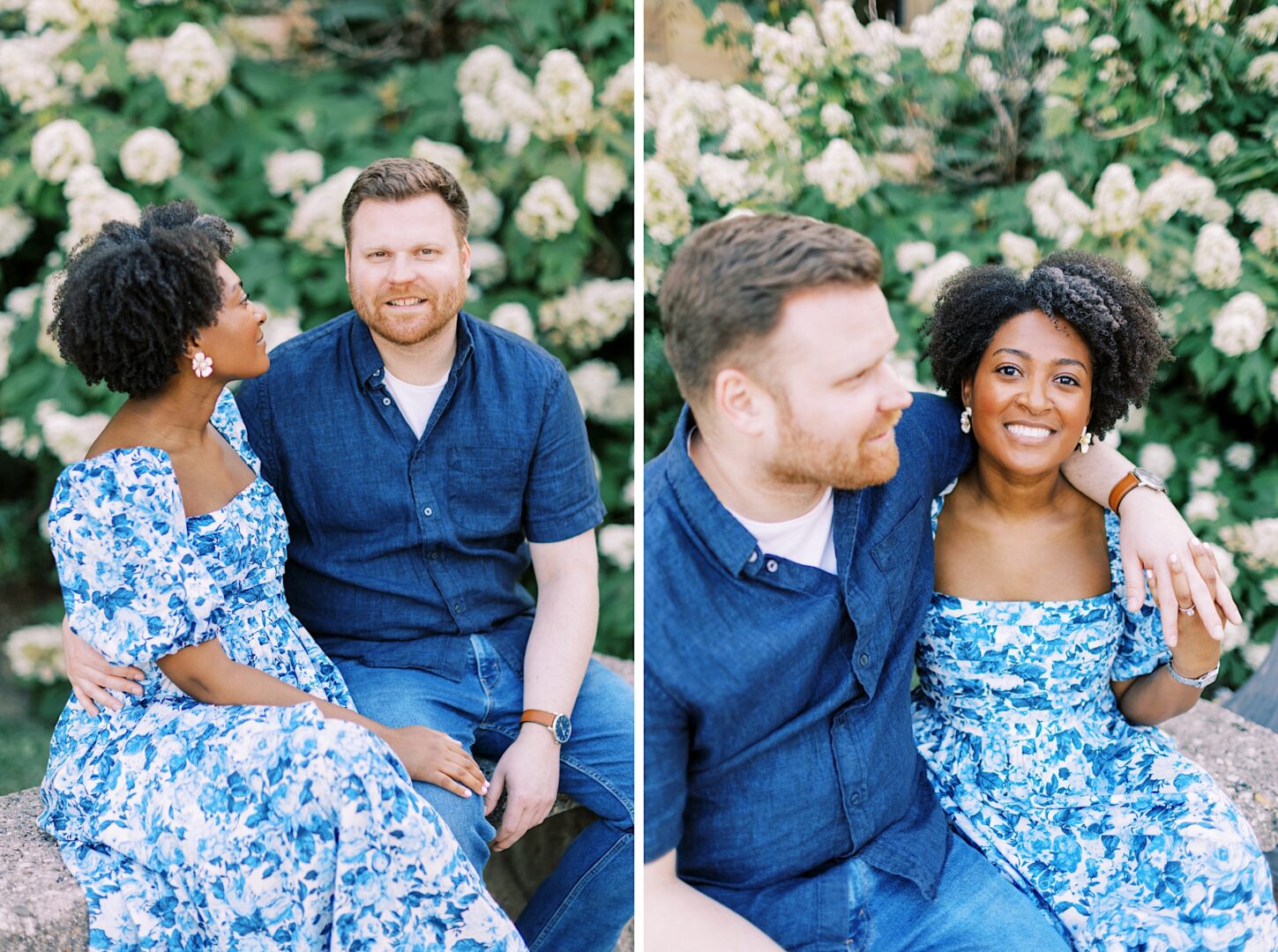 A couple sits together outdoors on a stone surface, surrounded by greenery and white flowers. The woman wears a blue floral dress; the man wears a short-sleeve, blue button-up shirt.