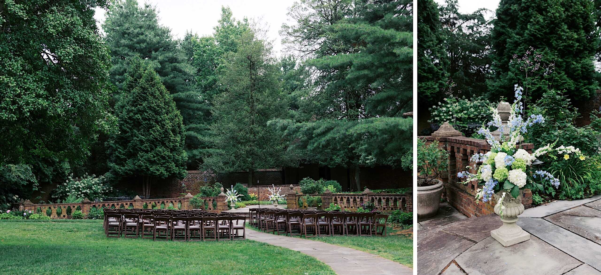 An outdoor Wedding at Aldie Mansion features rows of dark wooden chairs facing a floral arrangement, surrounded by lush greenery and majestic trees, with a charming stone pathway in the foreground.