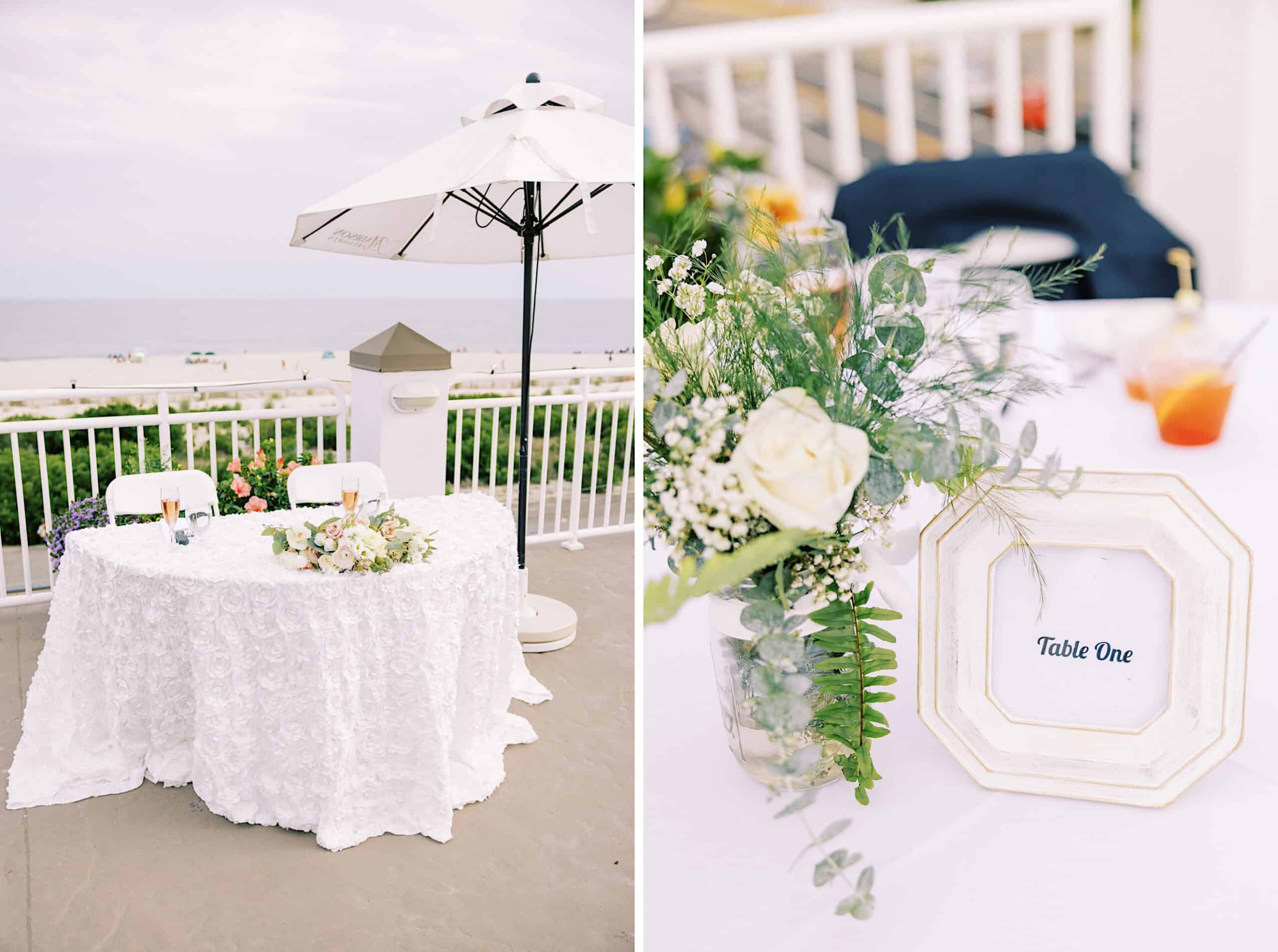 A round table with a white lace tablecloth, floral arrangement, and drinks on a patio by the beach at a Montreal Beach Resort Wedding; close-up of a “Table One” sign and flowers.