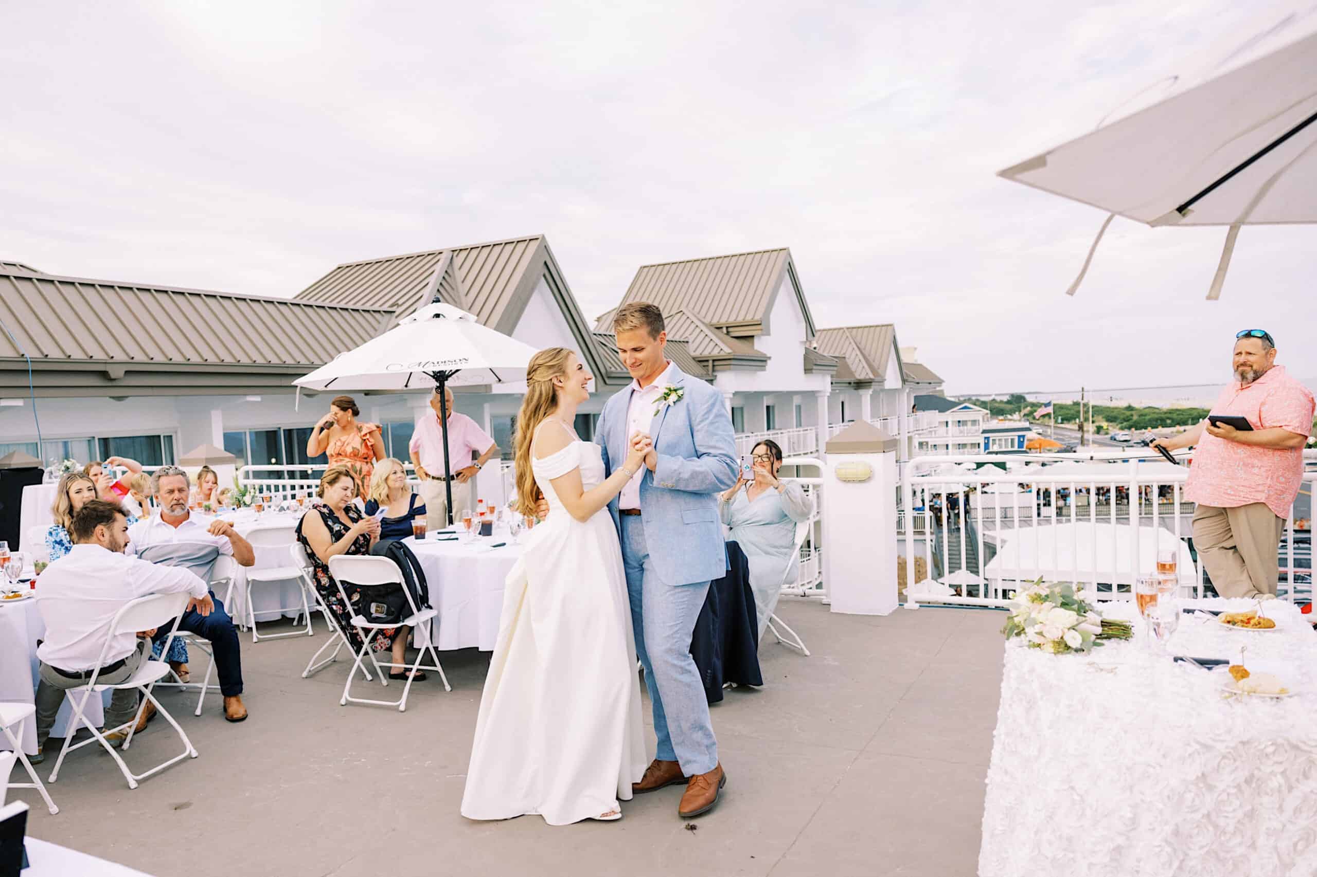 A bride and groom share their first dance on an outdoor patio at a Montreal Beach Resort Wedding, surrounded by seated guests during a daytime reception.