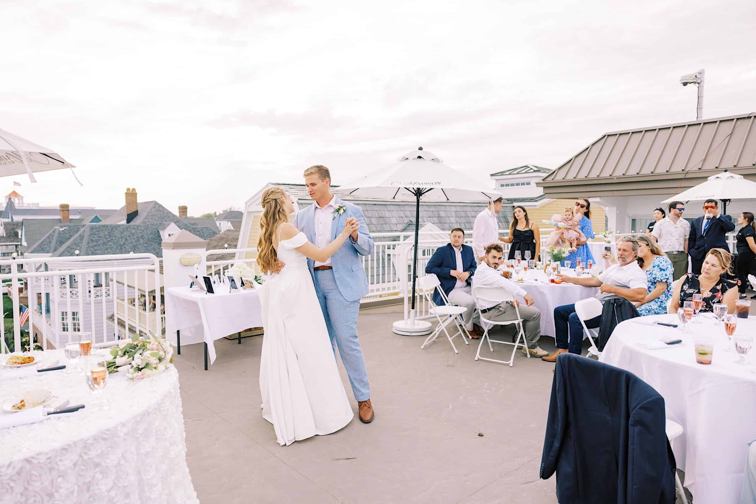 A bride and groom dance together on a rooftop patio at their Montreal Beach Resort wedding as guests watch from tables at a daytime outdoor reception.