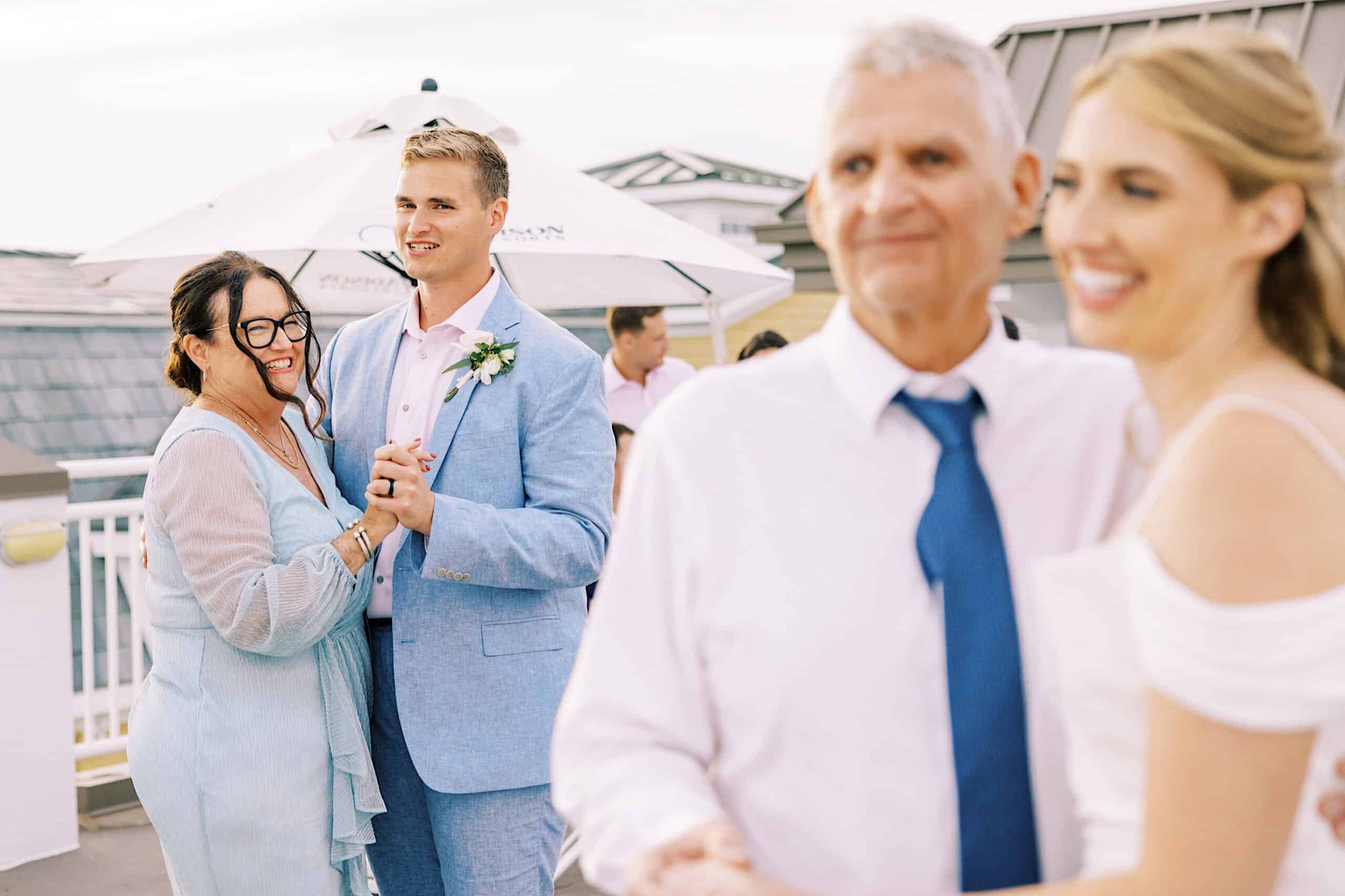Two couples dance outdoors at a rooftop Montreal Beach Resort Wedding; the pair in the background are smiling, while the foreground couple appears slightly out of focus.
