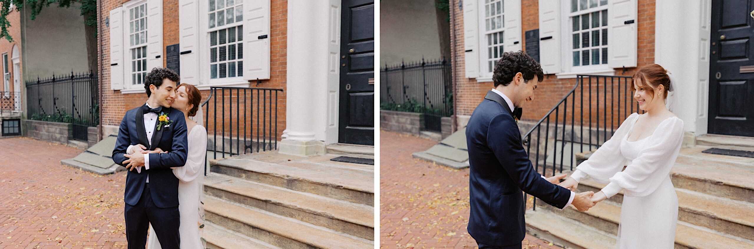 A couple in formal attire stands on the steps of a brick building, embracing and holding hands while smiling at each other.