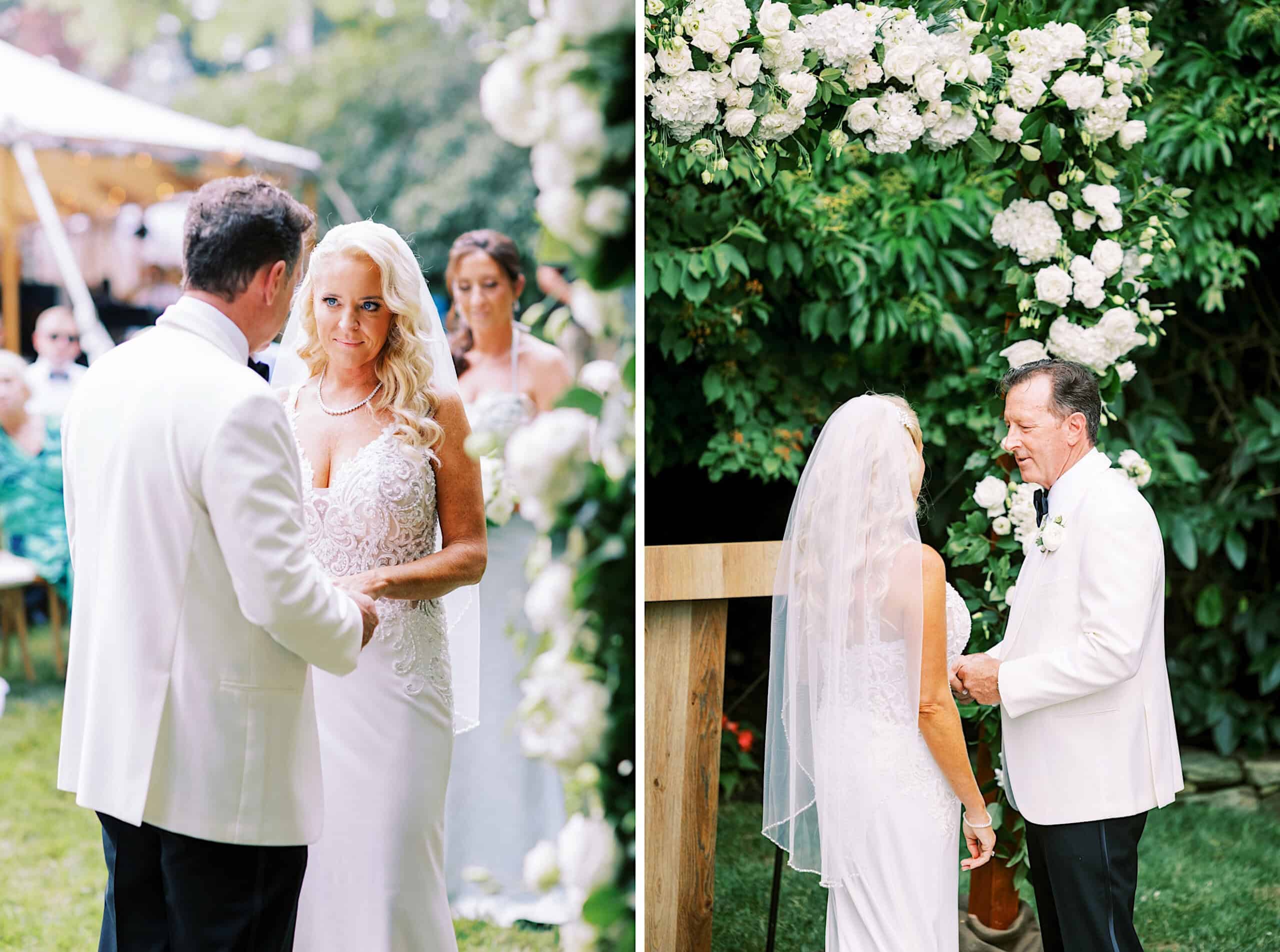 A bride and groom stand together outdoors during their romantic backyard wedding in NJ, holding hands beneath a beautiful floral arch.