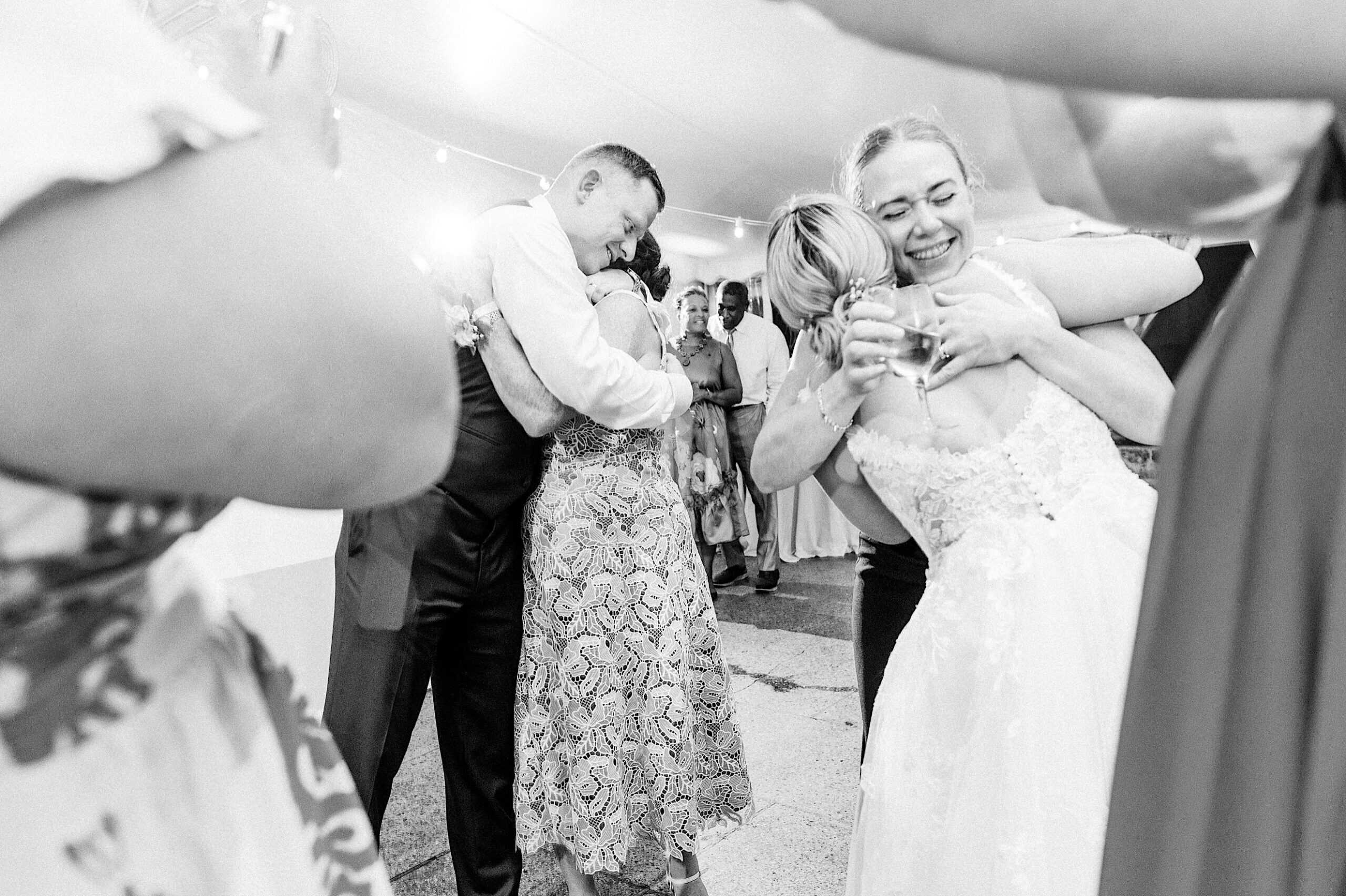 A bride and guests embrace and smile during a joyful moment at a lively Summer Wedding at Appleford Estate, the scene filled with emotion and celebration.