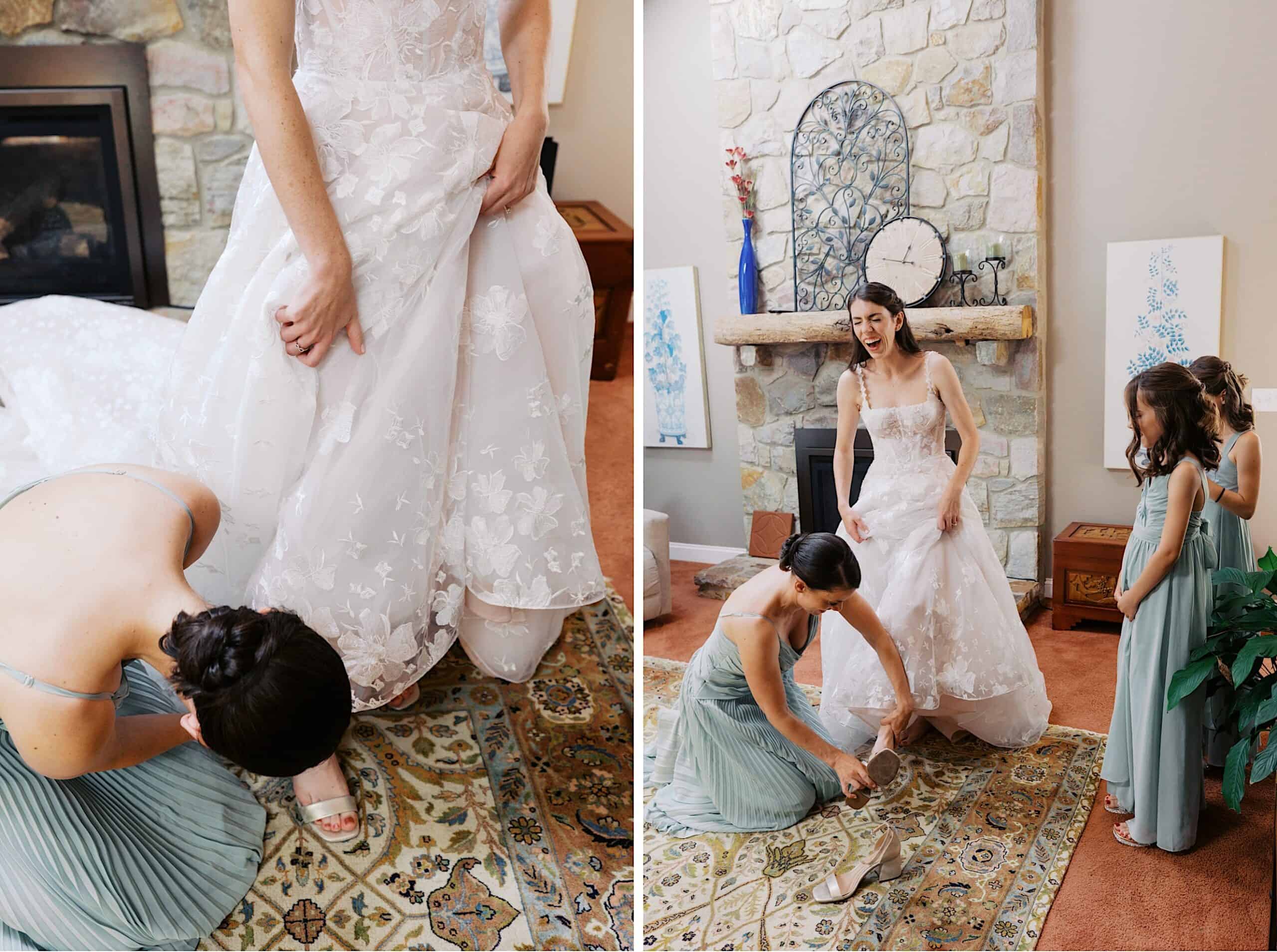 A bride in a floral lace gown stands as bridesmaids in green dresses help her adjust her dress and shoes in a living room with a stone fireplace, preparing for a luxurious wedding at The Ivy at Ellis Preserve.