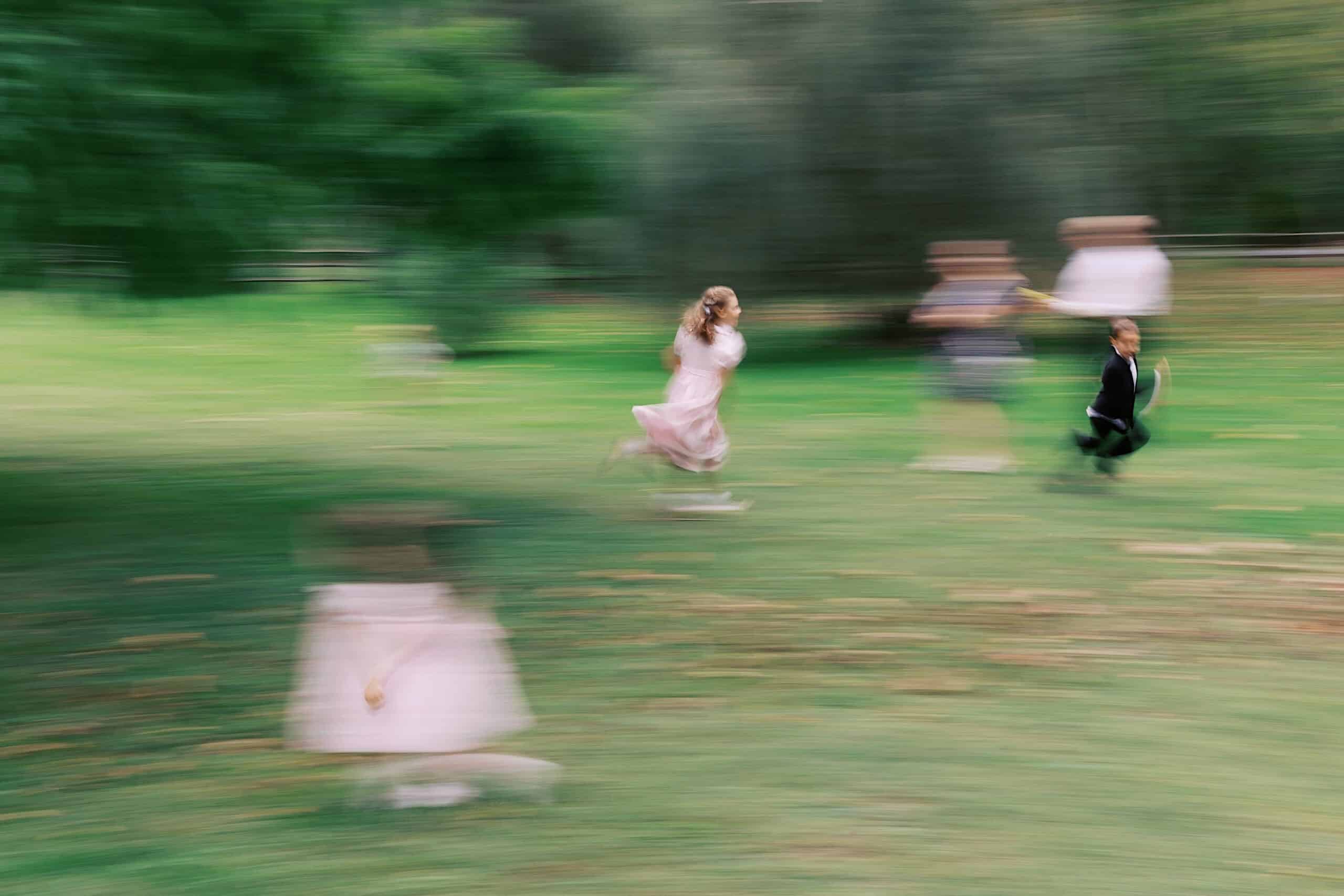 Children run and play on a grassy field during a beautiful wedding at Vincent Forge Mansion, with motion blur capturing their movement and adding a lively sense of speed and activity.