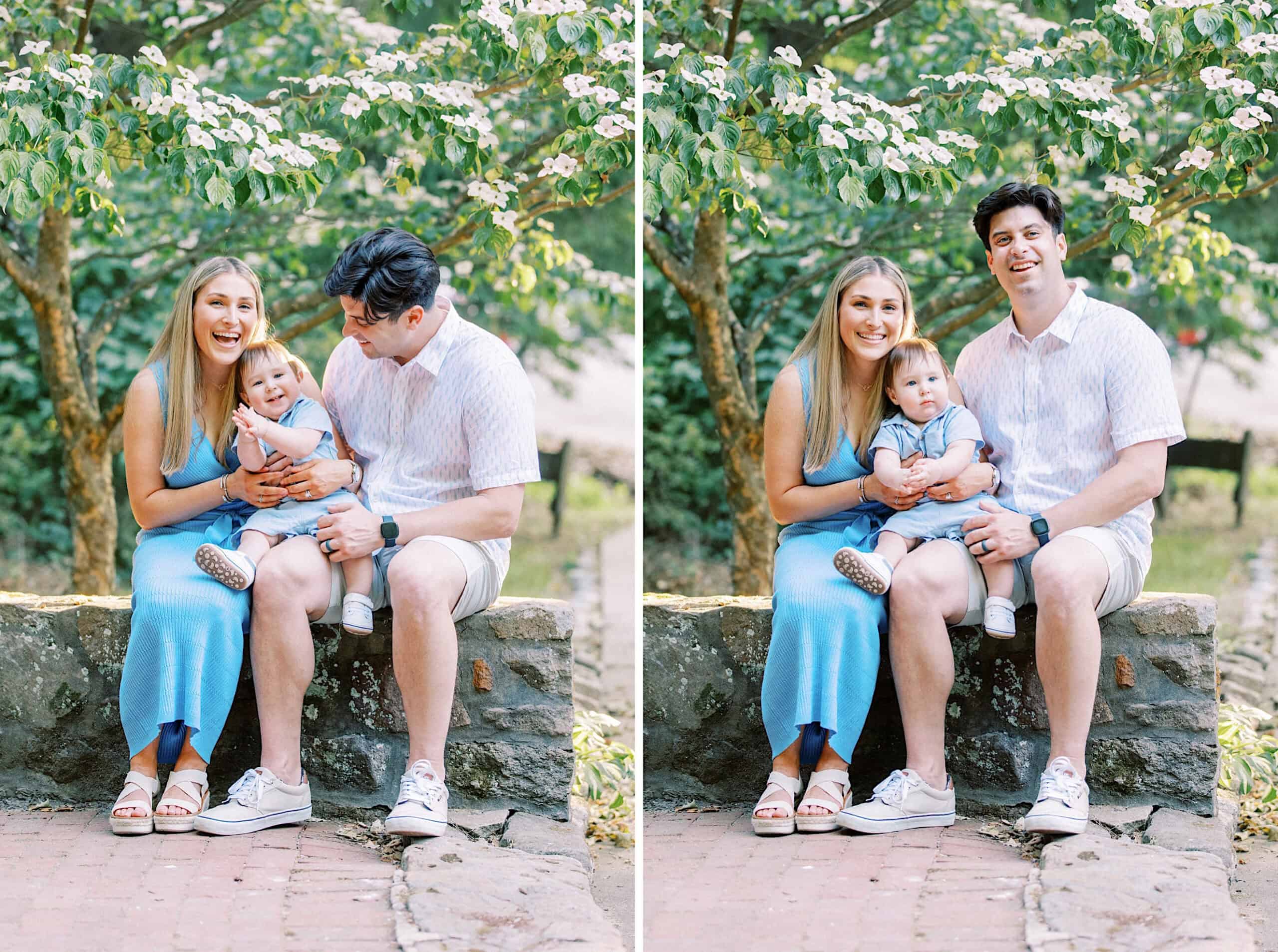 A family of three sits on a stone ledge outdoors for Spring Family Photos in Bucks County. The woman wears a blue dress, the man wears a white shirt and shorts, and their toddler sits between them, surrounded by green and leafy scenery.
