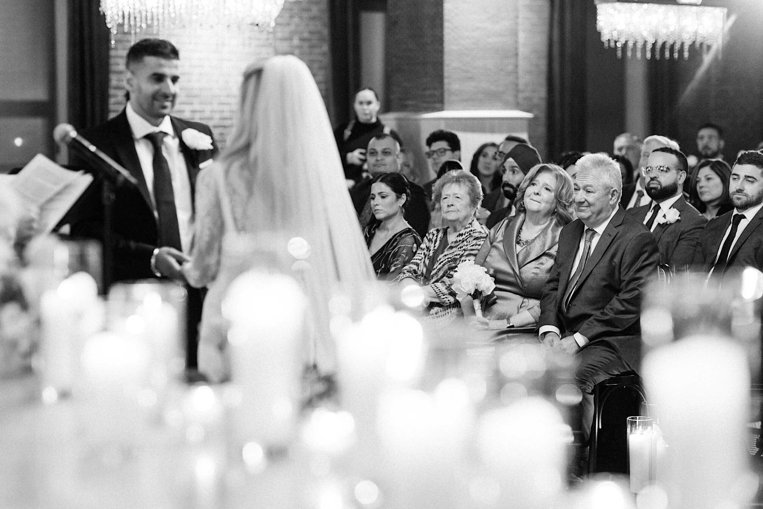 A bride and groom stand at the altar during an elegant Philadelphia Cescaphe Wedding at Tendenza, with guests seated and watching attentively in the background.