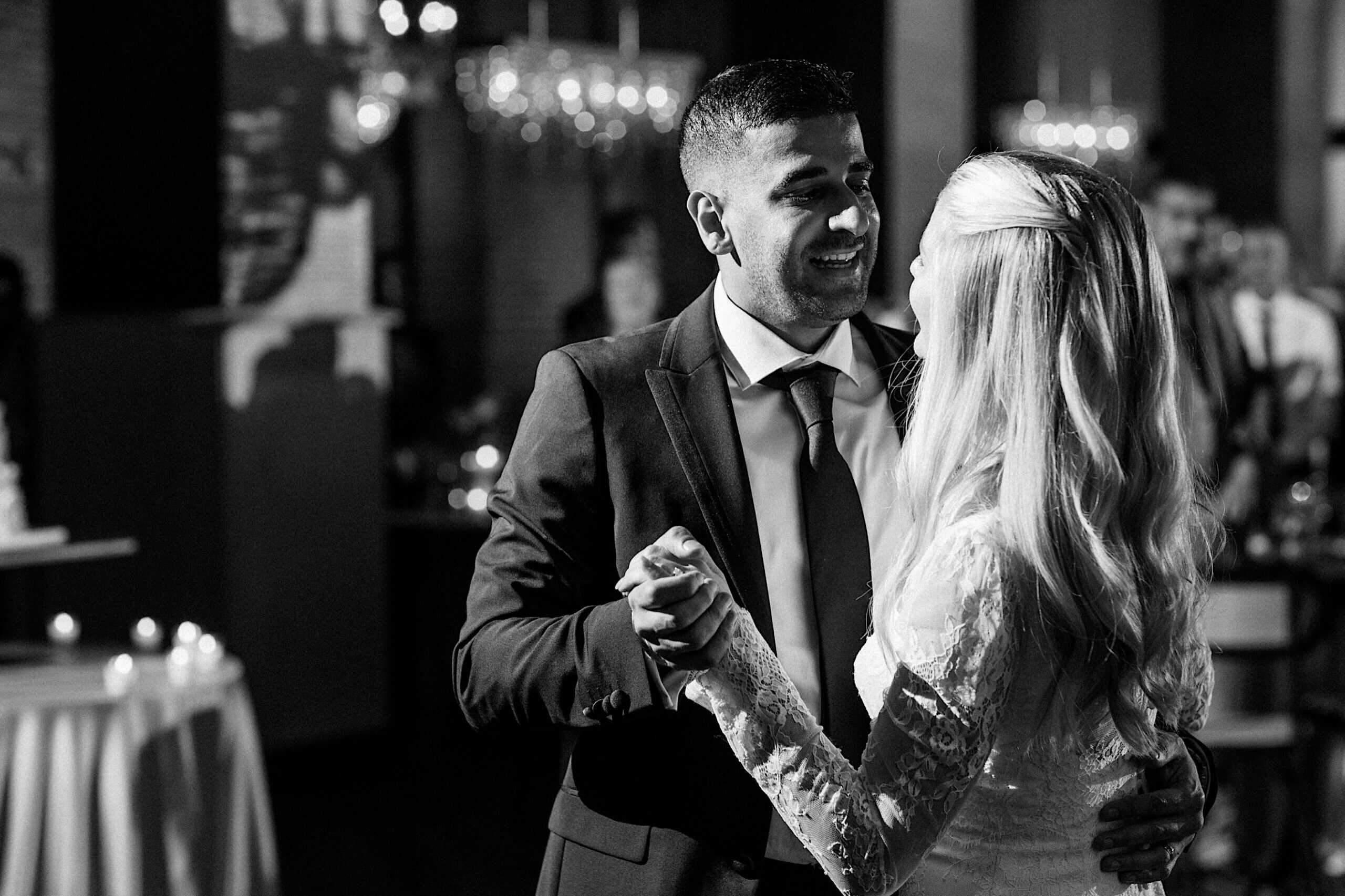 A man in a suit and a woman in a white dress are dancing together at an elegant Philadelphia Cescaphe Wedding at Tendenza, possibly during the wedding reception.