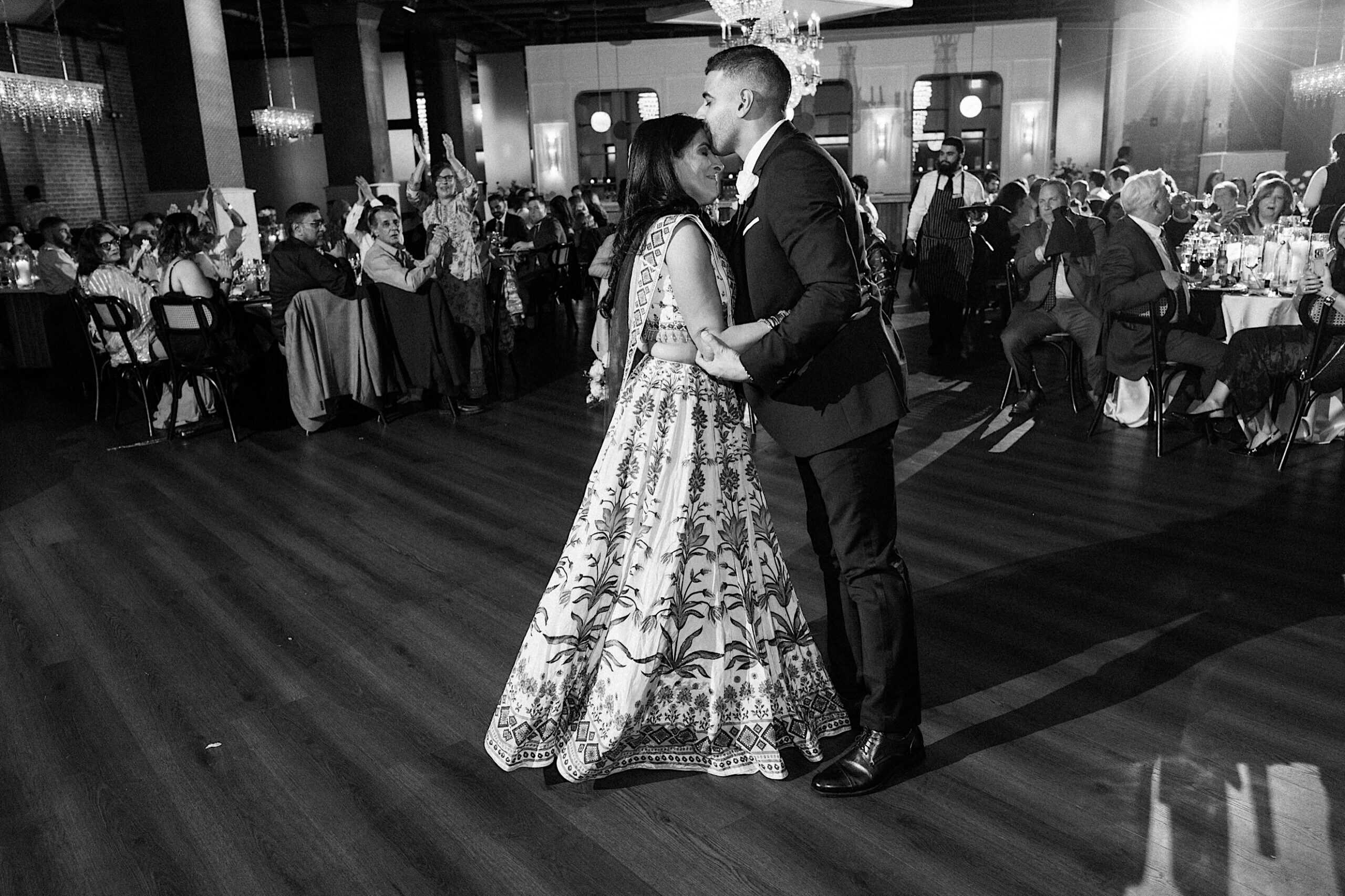 A man and woman dancing in a room with people in the background at an elegant Philadelphia Cescaphe Wedding at Tendenza.