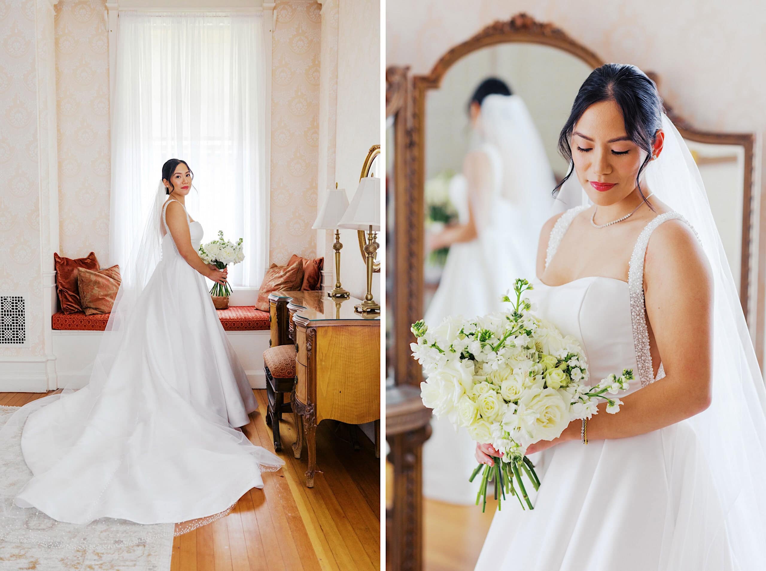 A bride in a white gown holding a bouquet of white flowers poses indoors next to a window and antique furniture, with a mirror reflecting her image at an elegant Cairnwood Estate Wedding.