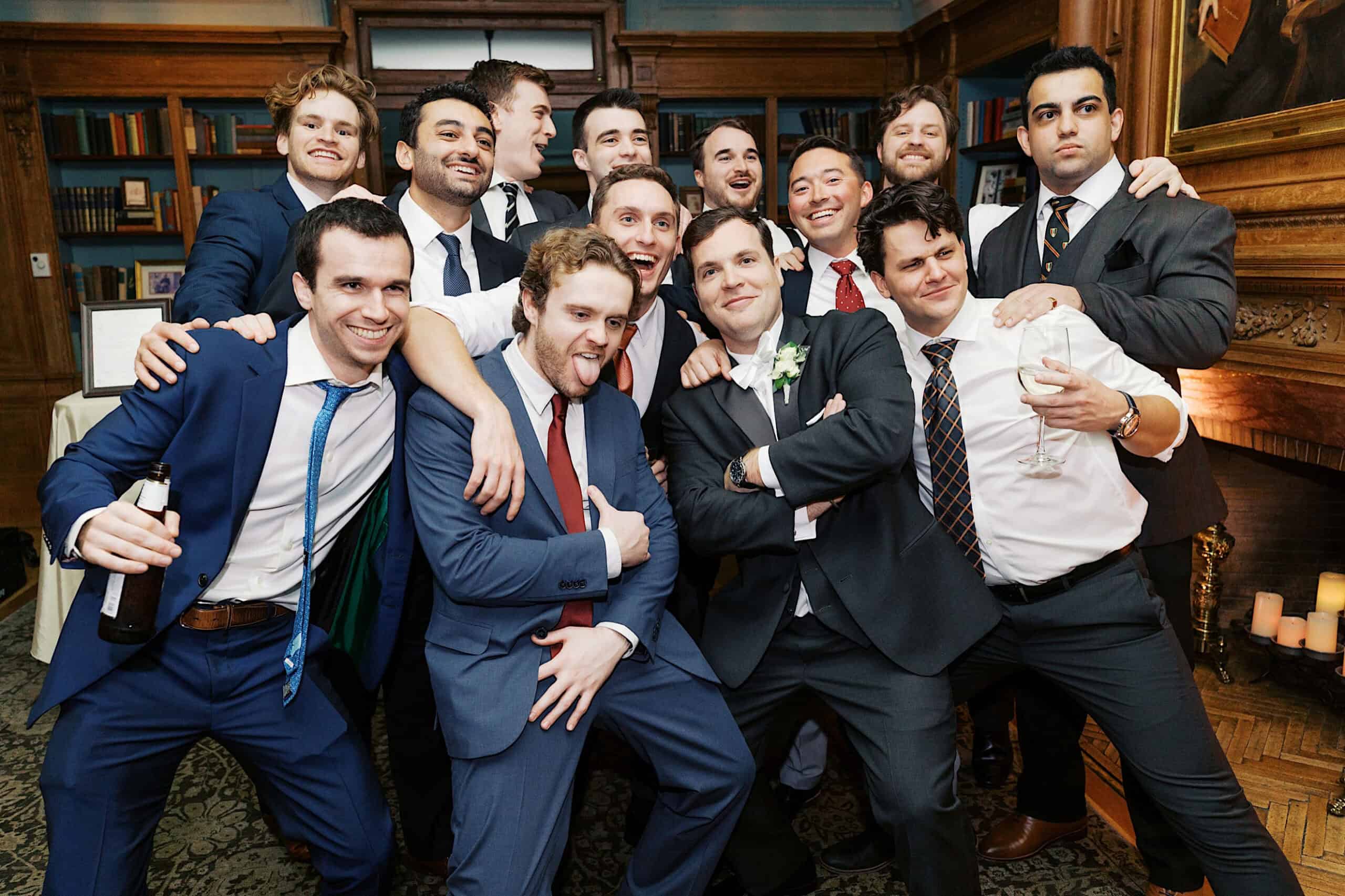 A group of men in suits pose together in a library-like room, smiling and celebrating at what appears to be an elegant Cairnwood Estate Wedding.