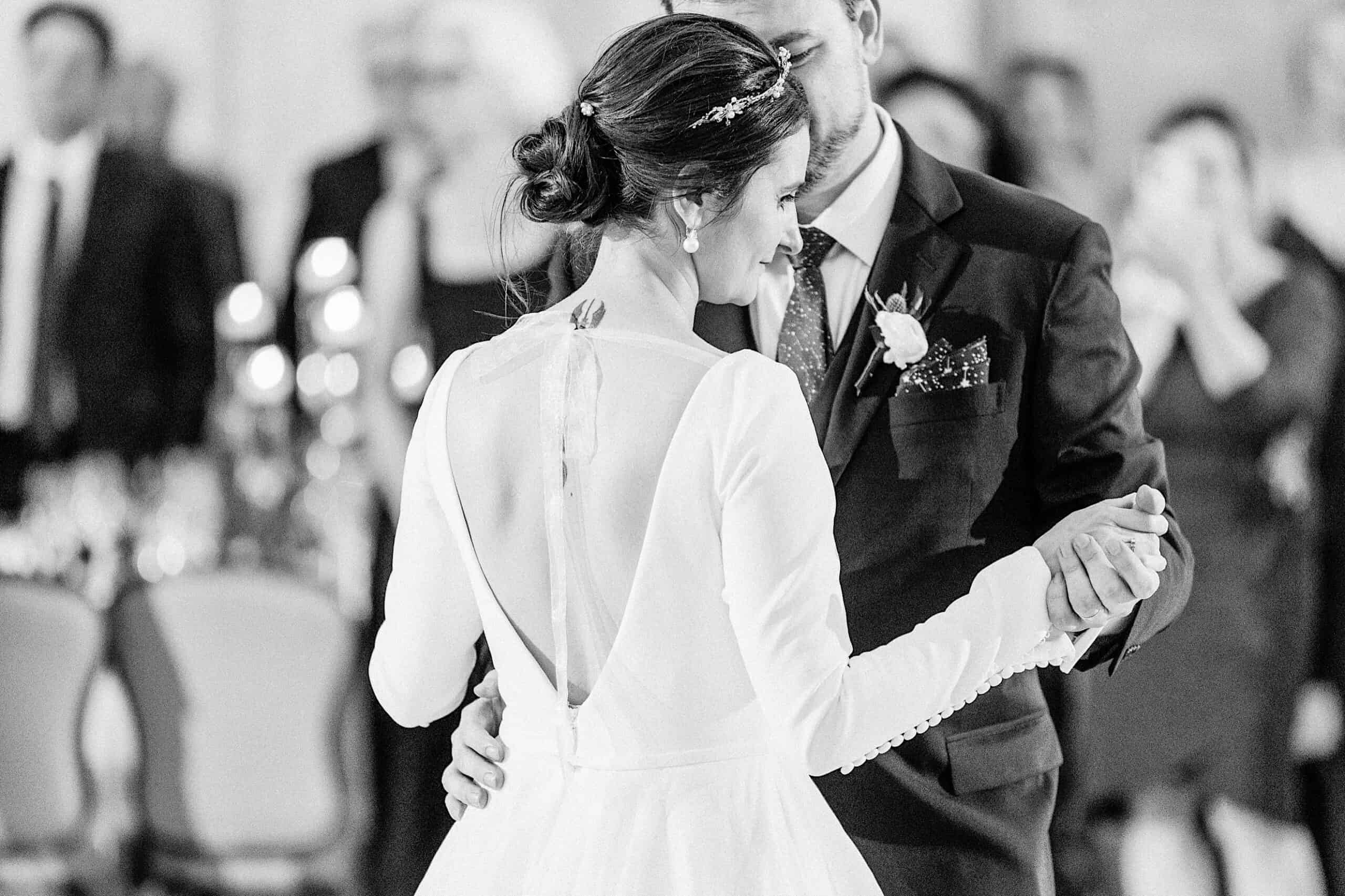 A bride and groom share a dance at their Franklin Institute wedding reception, with guests and tables visible in the blurred background.