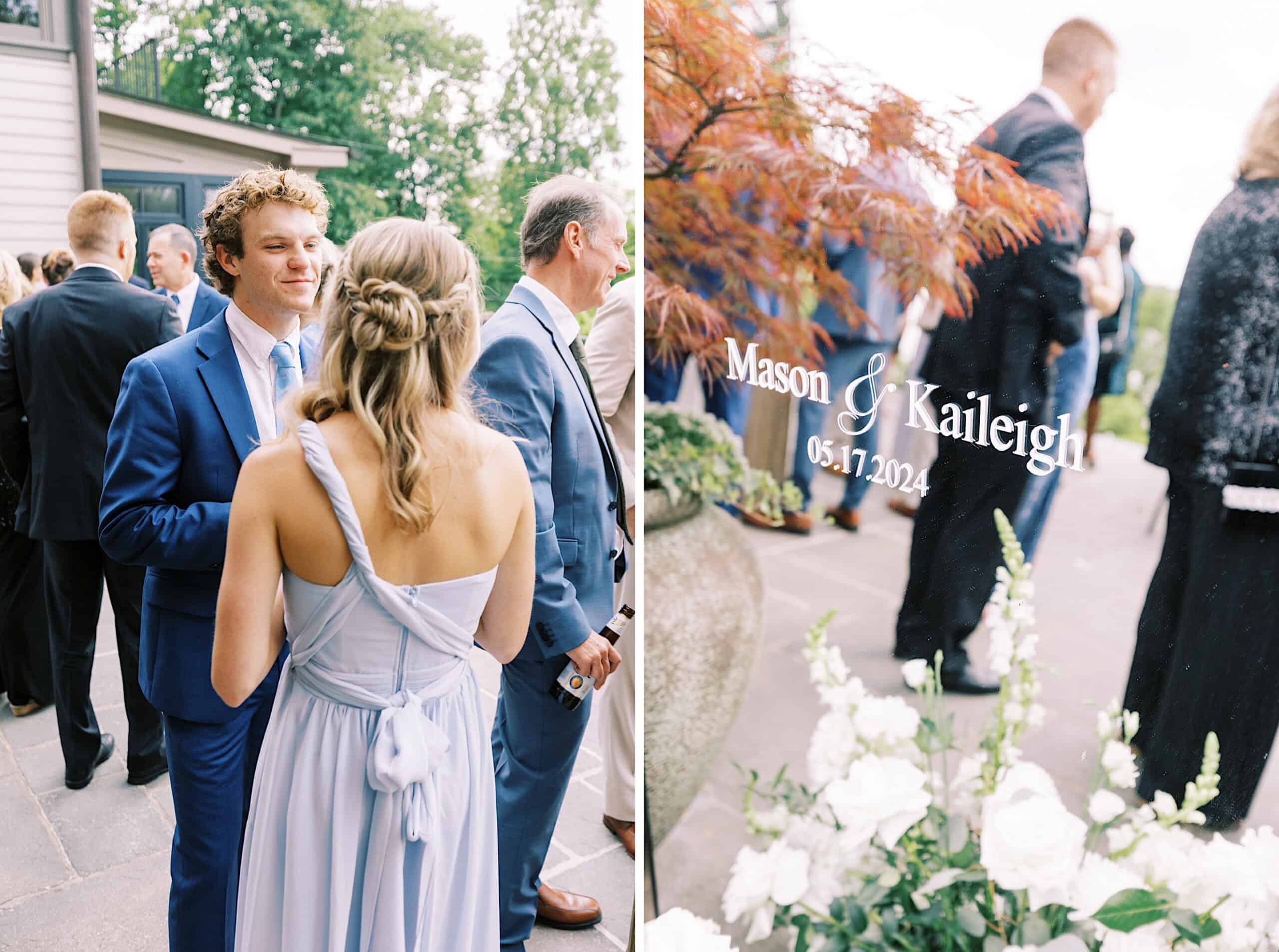 Guests in formal attire converse outdoors at a Lake House Inn Wedding; a decorative sign displays "Mason & Kaileigh 05.17.2024" beside flowers and a potted plant.