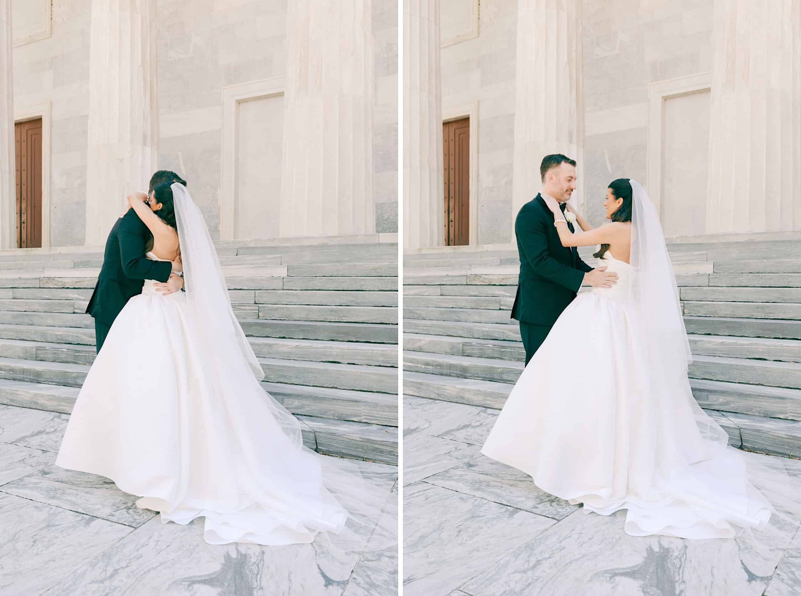 A bride and groom in formal wedding attire stand on marble steps, embracing and looking at each other in front of a building with tall stone columns—capturing the elegance of a Classic Wedding at Ballroom at the Ben.