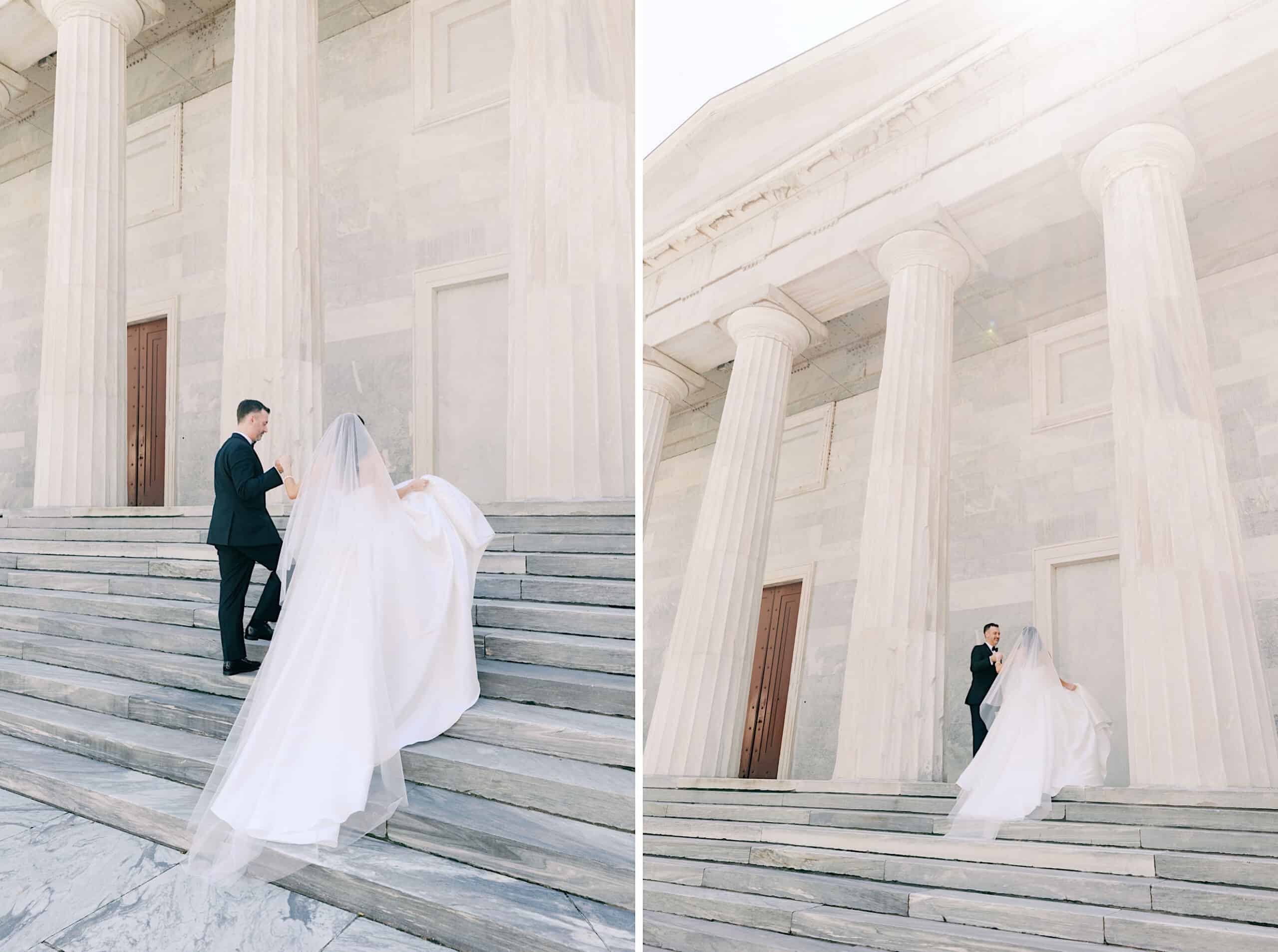 A bride and groom walk up wide marble steps outside a building with tall columns and stone walls, capturing the elegance of a Classic Wedding at Ballroom at the Ben. The bride wears a long white gown and veil.