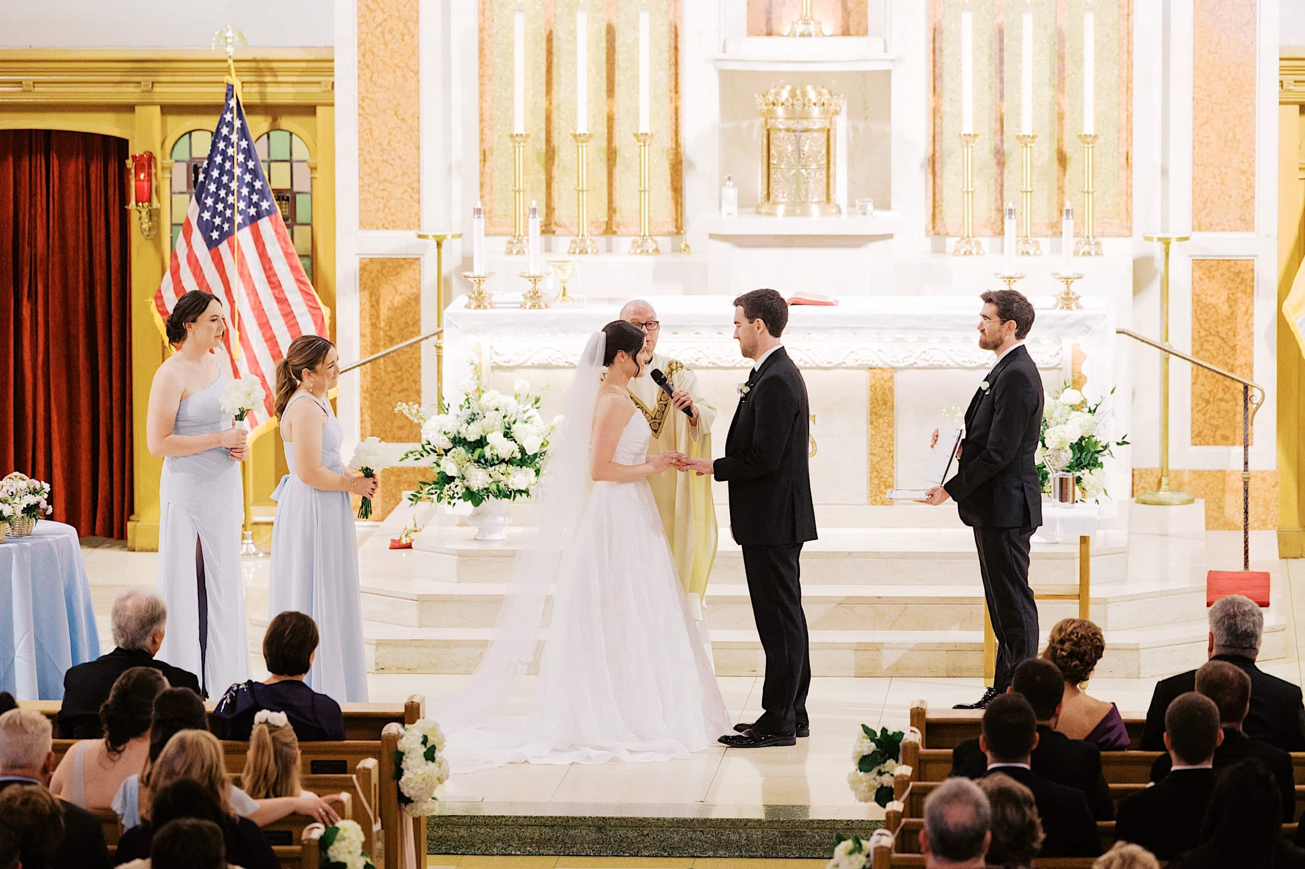 Bride and groom stand facing each other at the altar during a The Ivy at Ellis Preserve spring wedding, with attendants and guests present in the church.