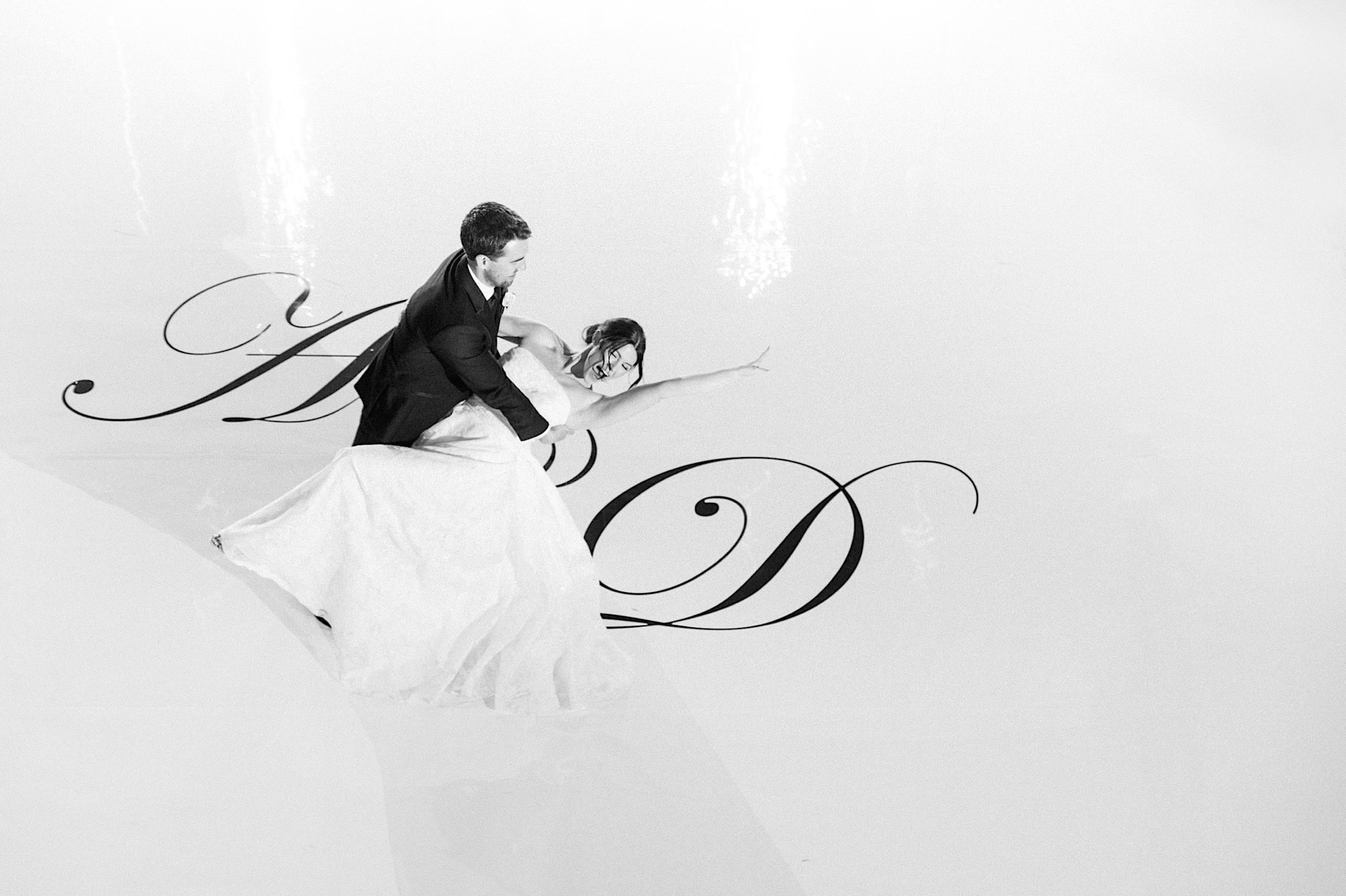 A bride and groom dance on a white floor with large decorative script letters at their The Ivy at Ellis Preserve spring wedding.