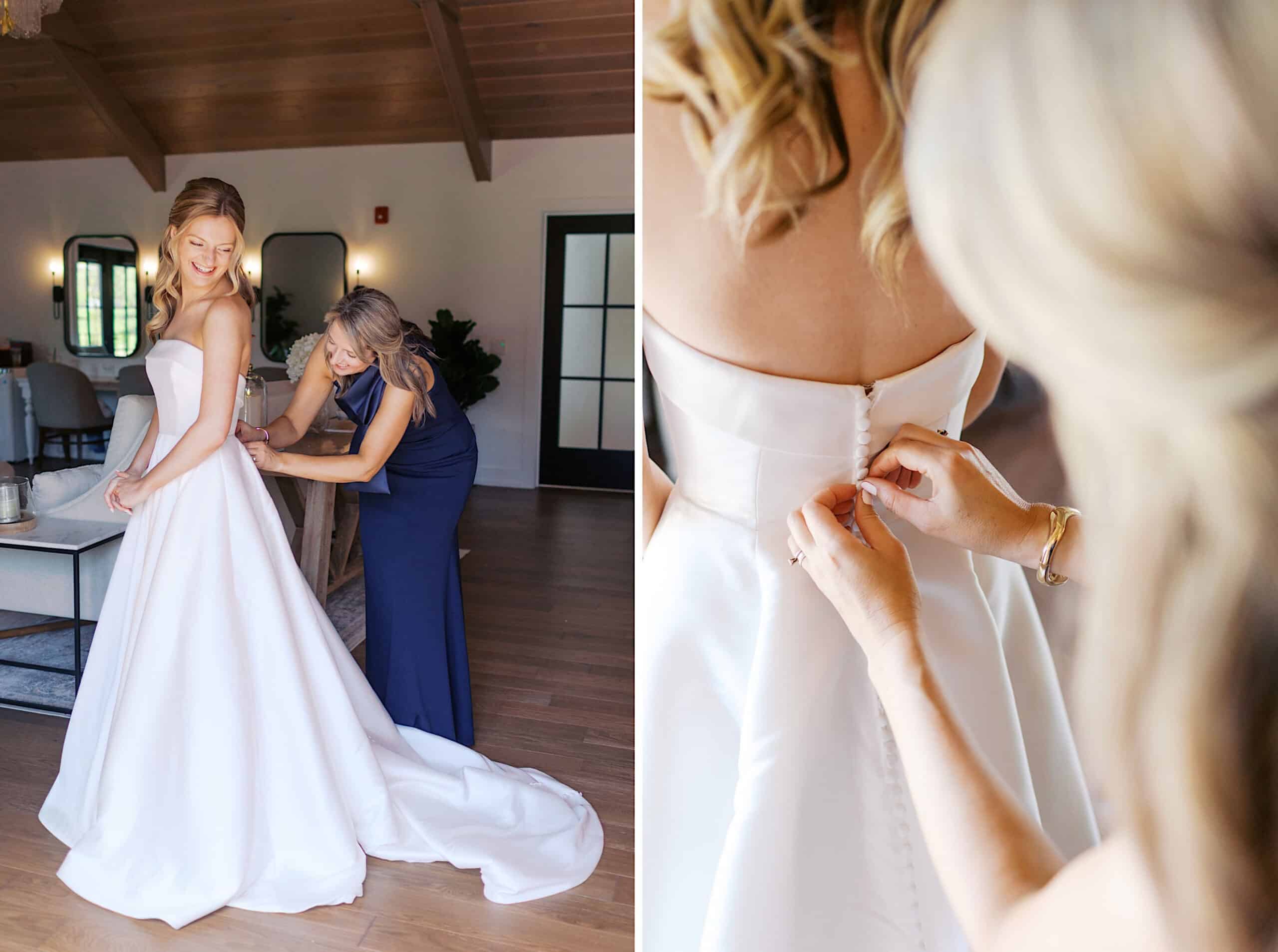 At a Westwynd Gardens Spring Wedding, a woman in a white wedding dress is assisted by another woman in a blue dress, who is fastening the buttons on the back of the gown.