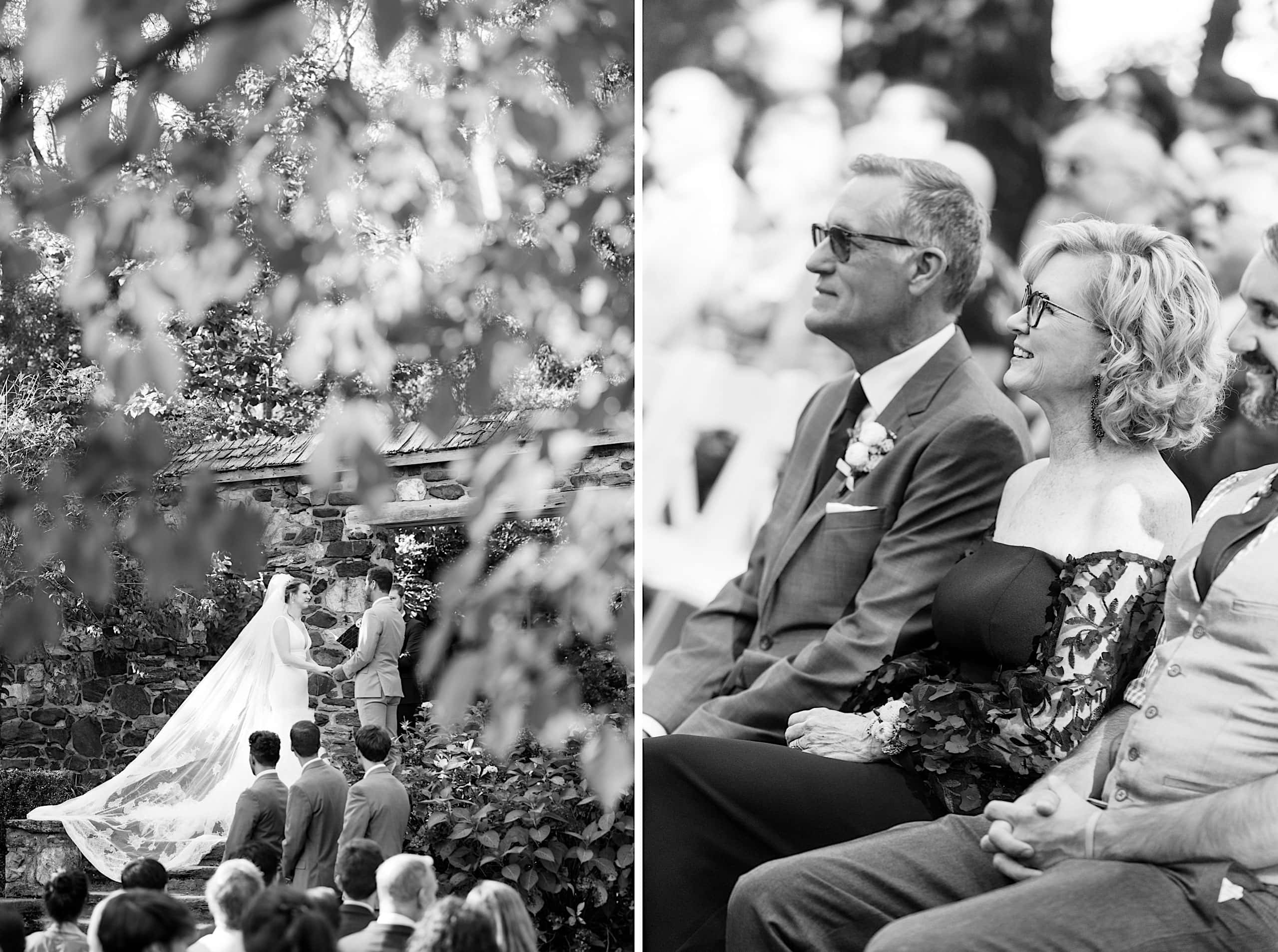 A bride and groom stand together outdoors during a Parque Ridley Creek garden ceremony; guests, including an older couple, watch from their seats.