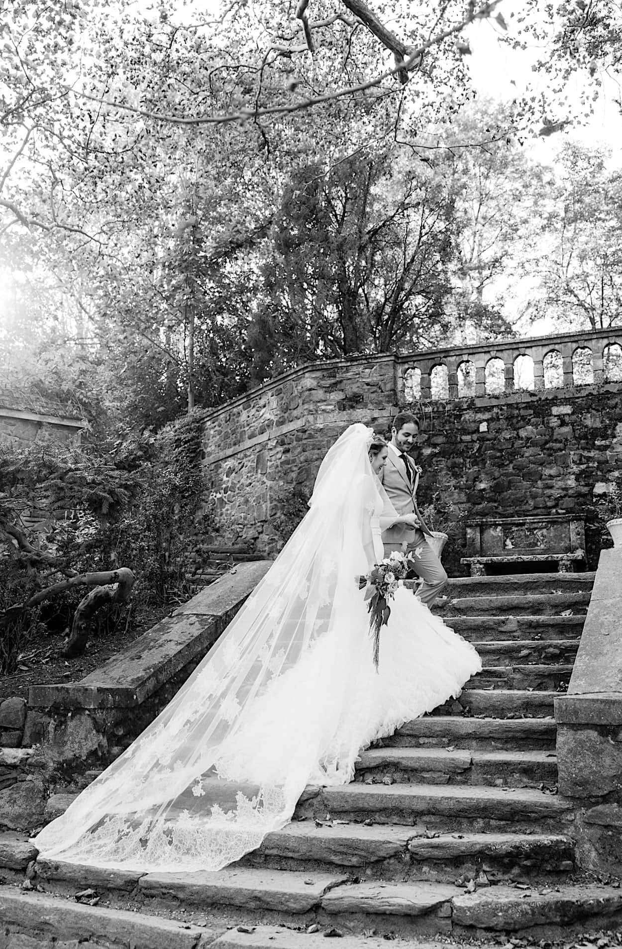 A bride and groom on the outdoor stone steps of Parque Ridley Creek, and a close-up of them under a veil; both photos are in black and white, capturing the elegance of their garden ceremony.